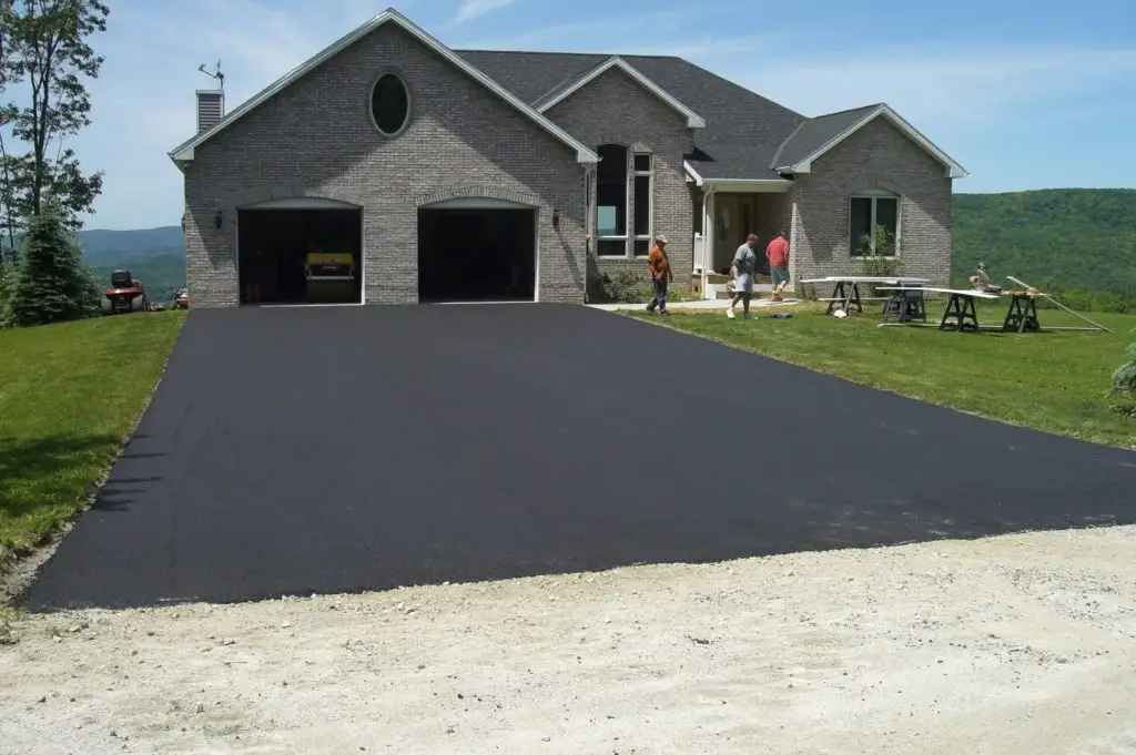 New asphalt driveway in front of a stone home